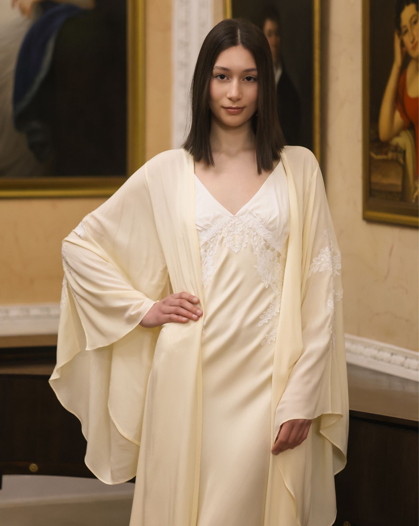 A mid-length shot focusing on the lace appliqué at the bodice and the wide sleeves edged in delicate lace.