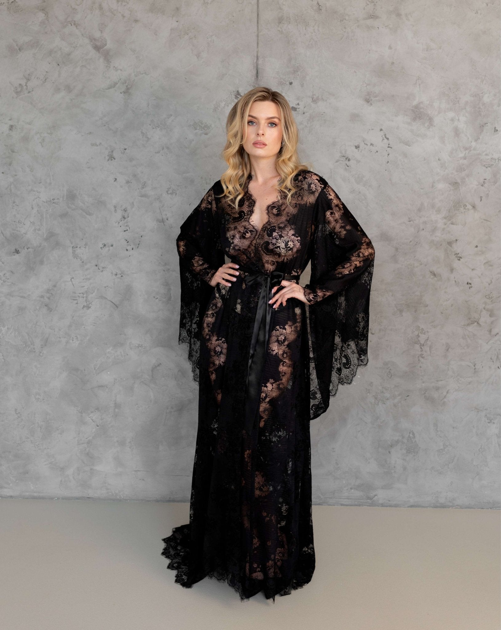 Bride in white lace robe with long train, standing in front of wooden backdrop – KÂfemme