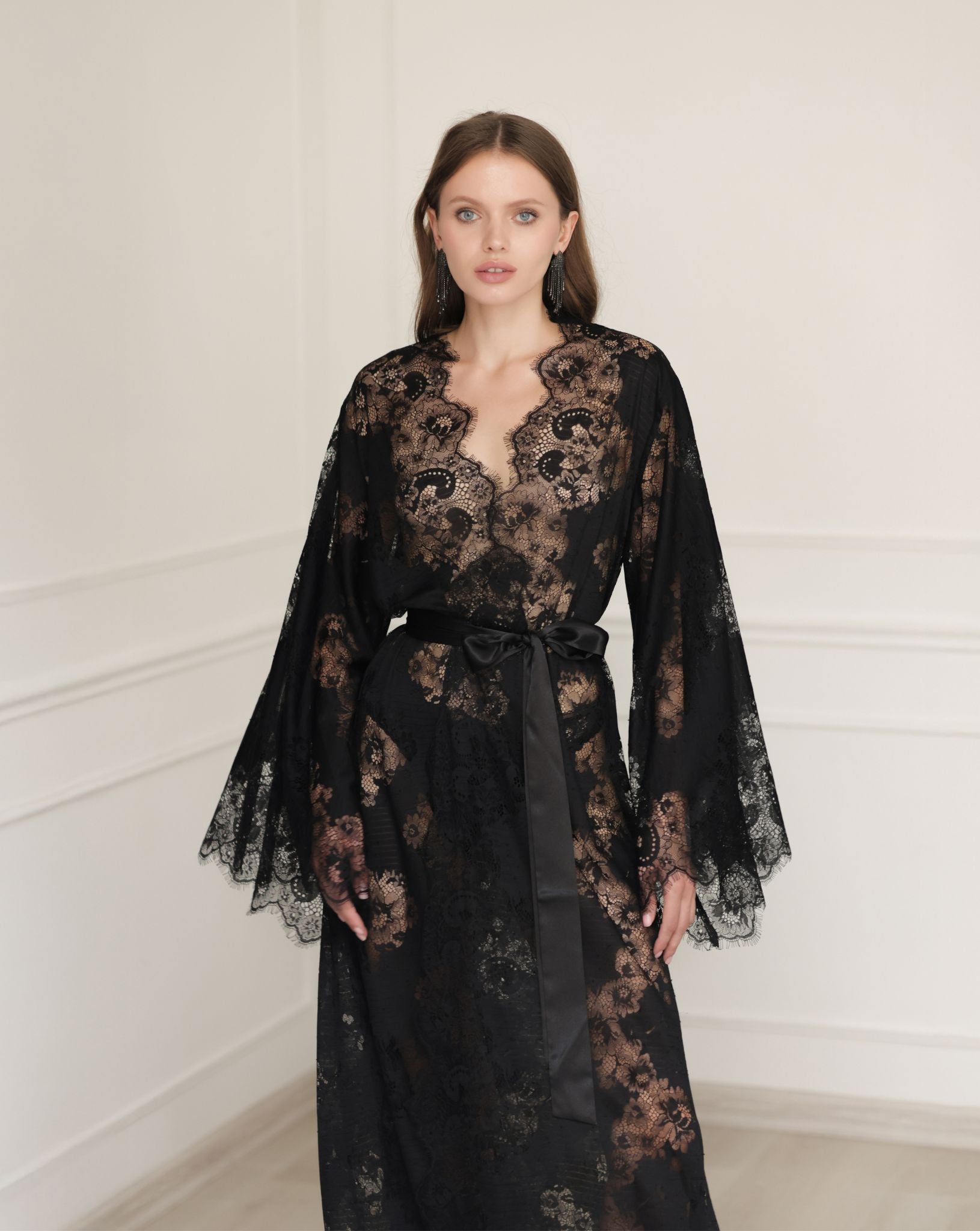 Mid-length shot of a flowing black robe in motion, highlighting the airy lace sleeves and elegant wrap-over style.