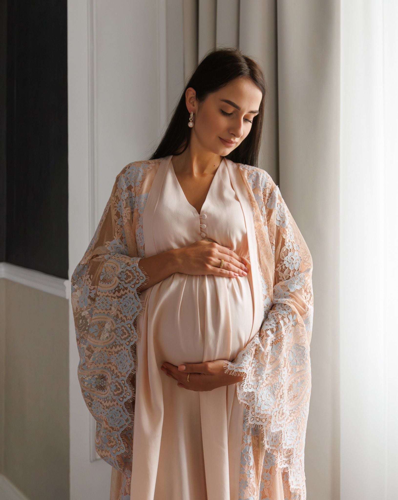 Mid-length shot of a mother-to-be in a lace wrap, highlighting the sophisticated style and easy nursing access buttons.