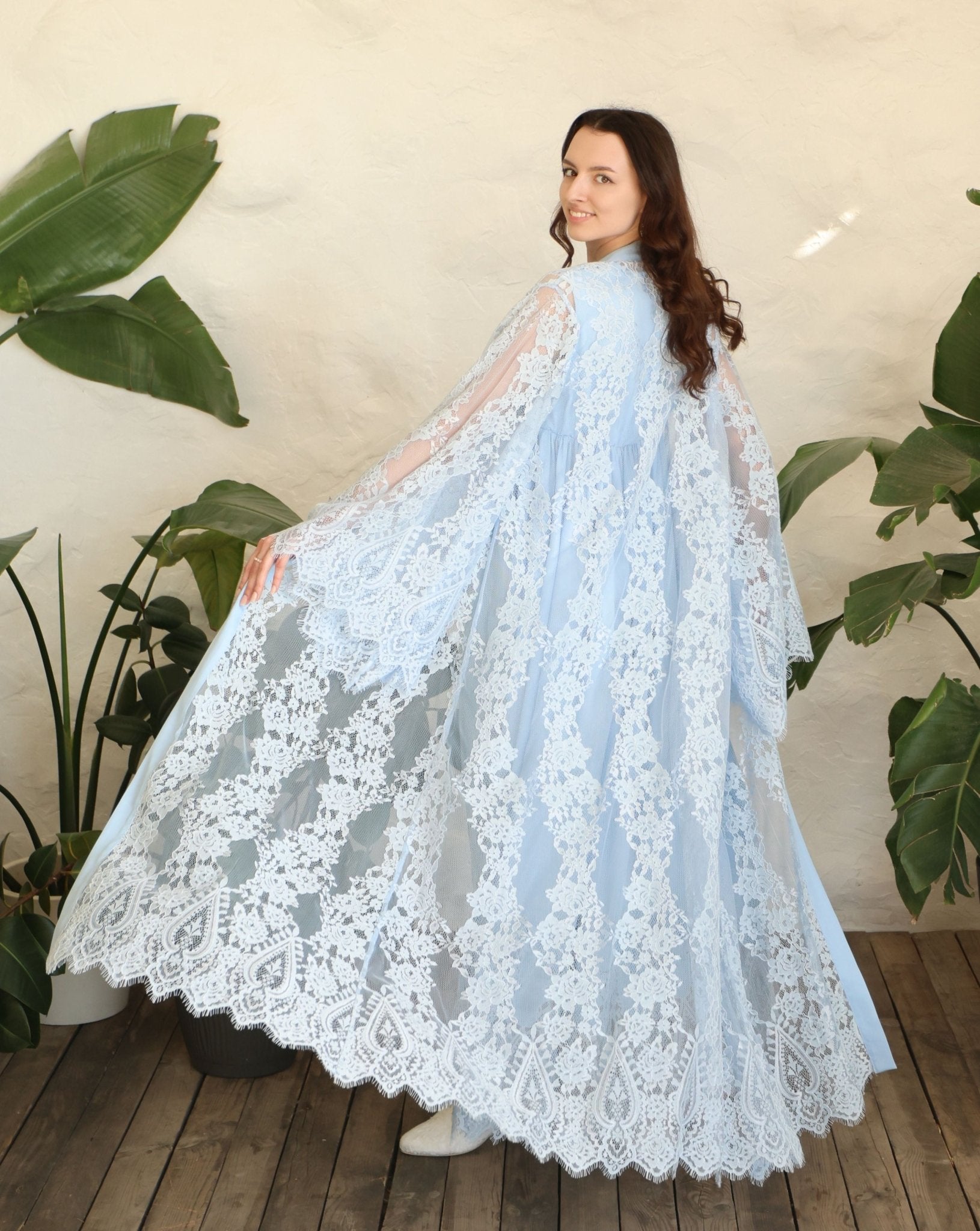 Rear view of the robe in motion, highlighting the voluminous lace and the graceful drape over the body.