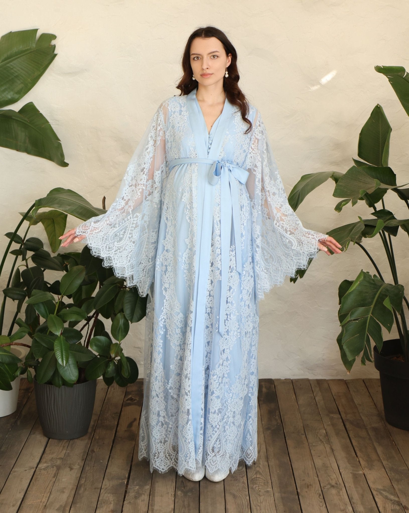 A frontal shot with raised arms, showcasing the voluminous lace sleeves and the charming finish of the robe.