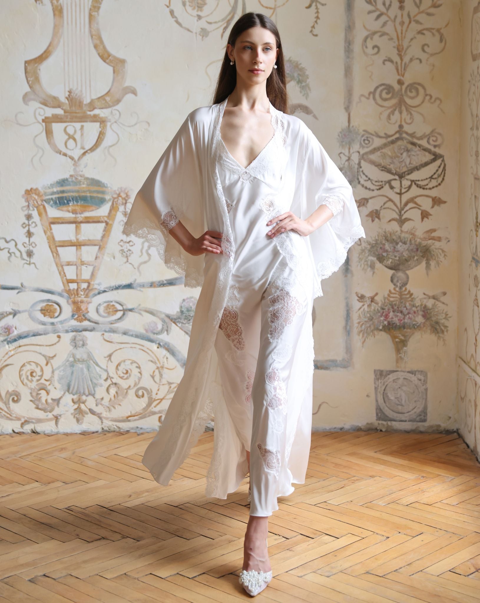 White Robe and Nightgown Set in motion, featuring flowing fabrics and delicate floral lace appliqués in full length.