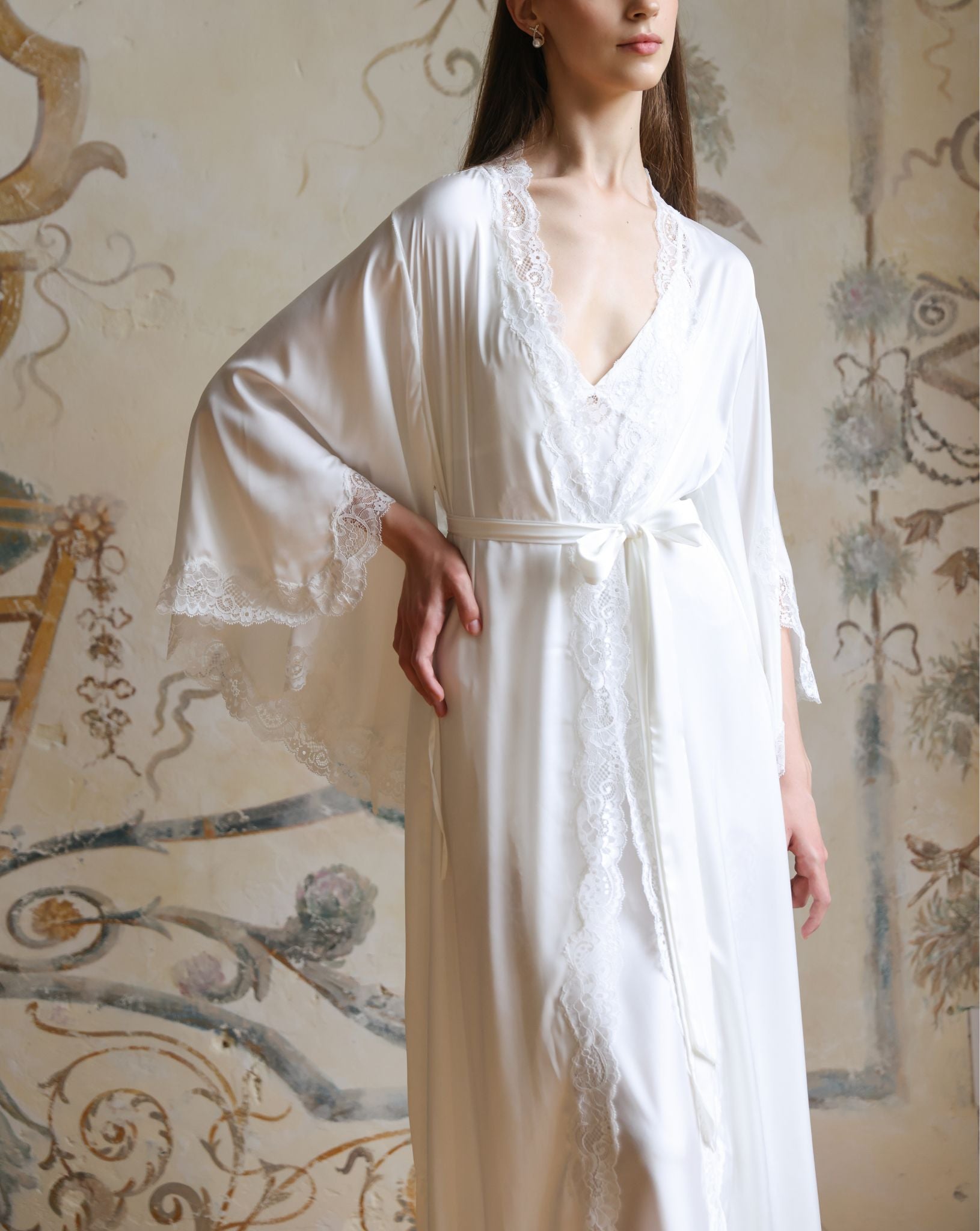 Waist-up shot of the white robe flowing gracefully, focusing on the wide sleeves and artistic floral lace appliqués.