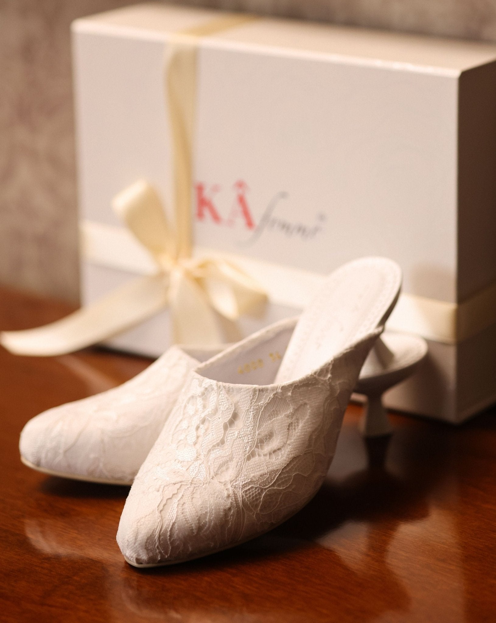 Elegant footwear presented next to its branded box, reflecting a refined essential made for special moments.