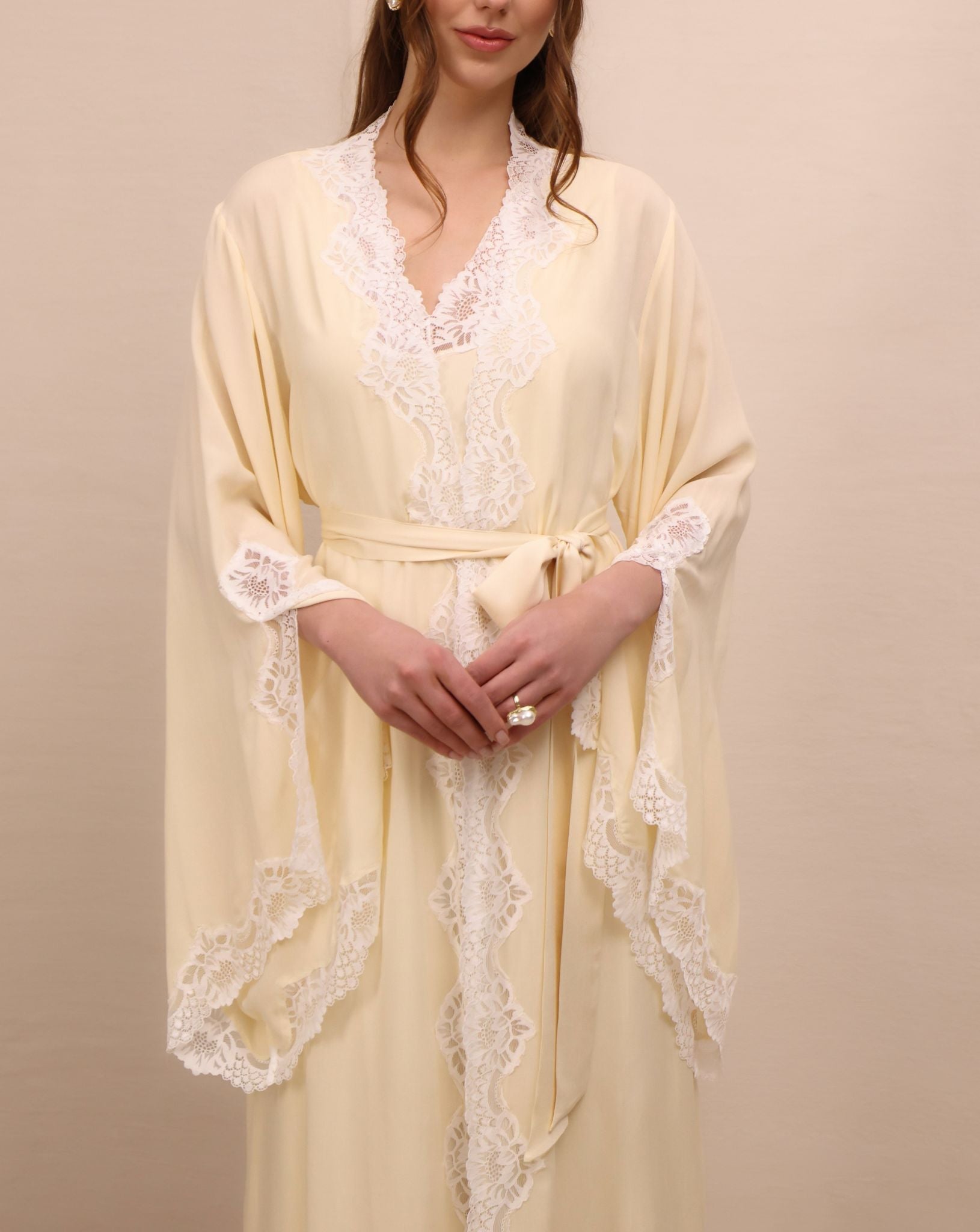 A mid-length shot focusing on the intricate lace and sleeve slits that add movement to the elegant silhouette.