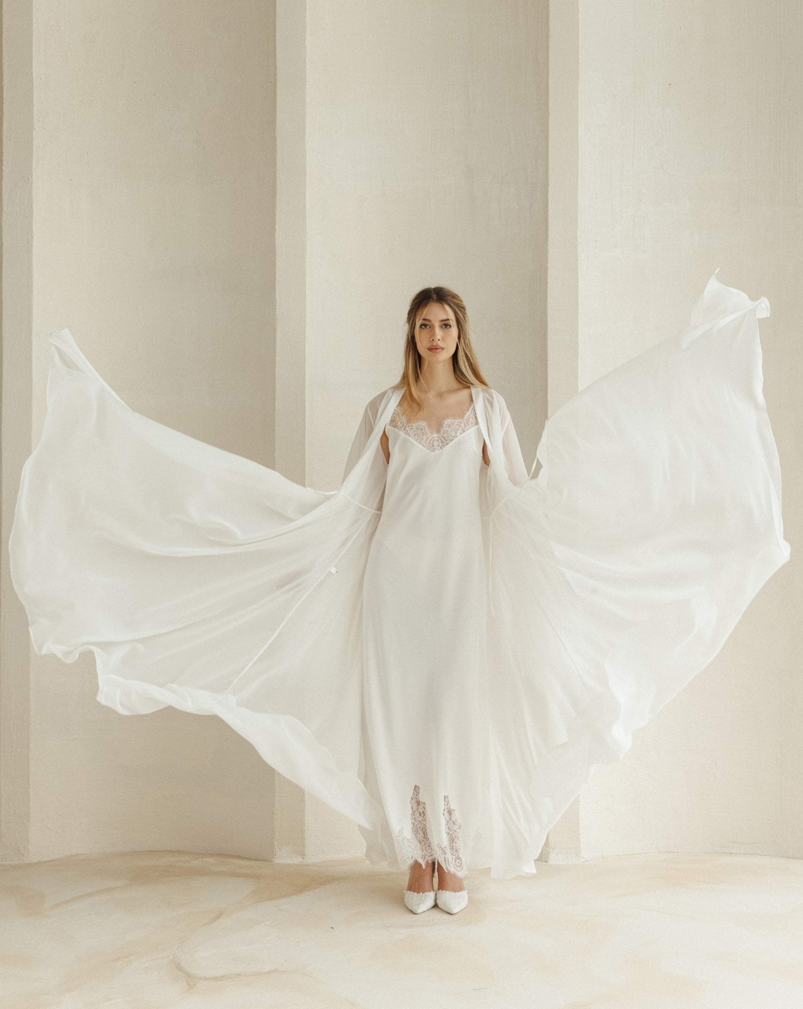 Long bridal robe thrown up to show its full, voluminous sweep and light, airy fabric in a dramatic pose.