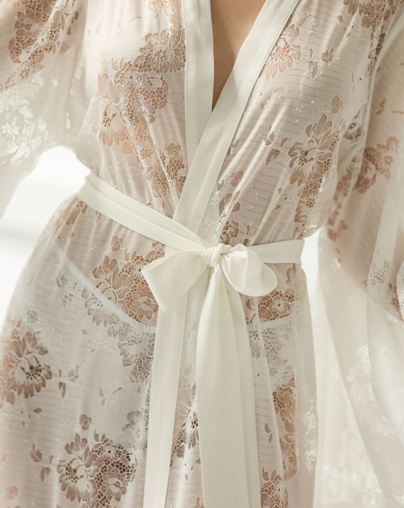 Detailed shot from neck to waist, focusing on the wrap-over style and the beautifully tied lace belt.