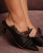 Detailed close-up of the footwear on feet, focusing on the intricate lace details and the soft satin base.