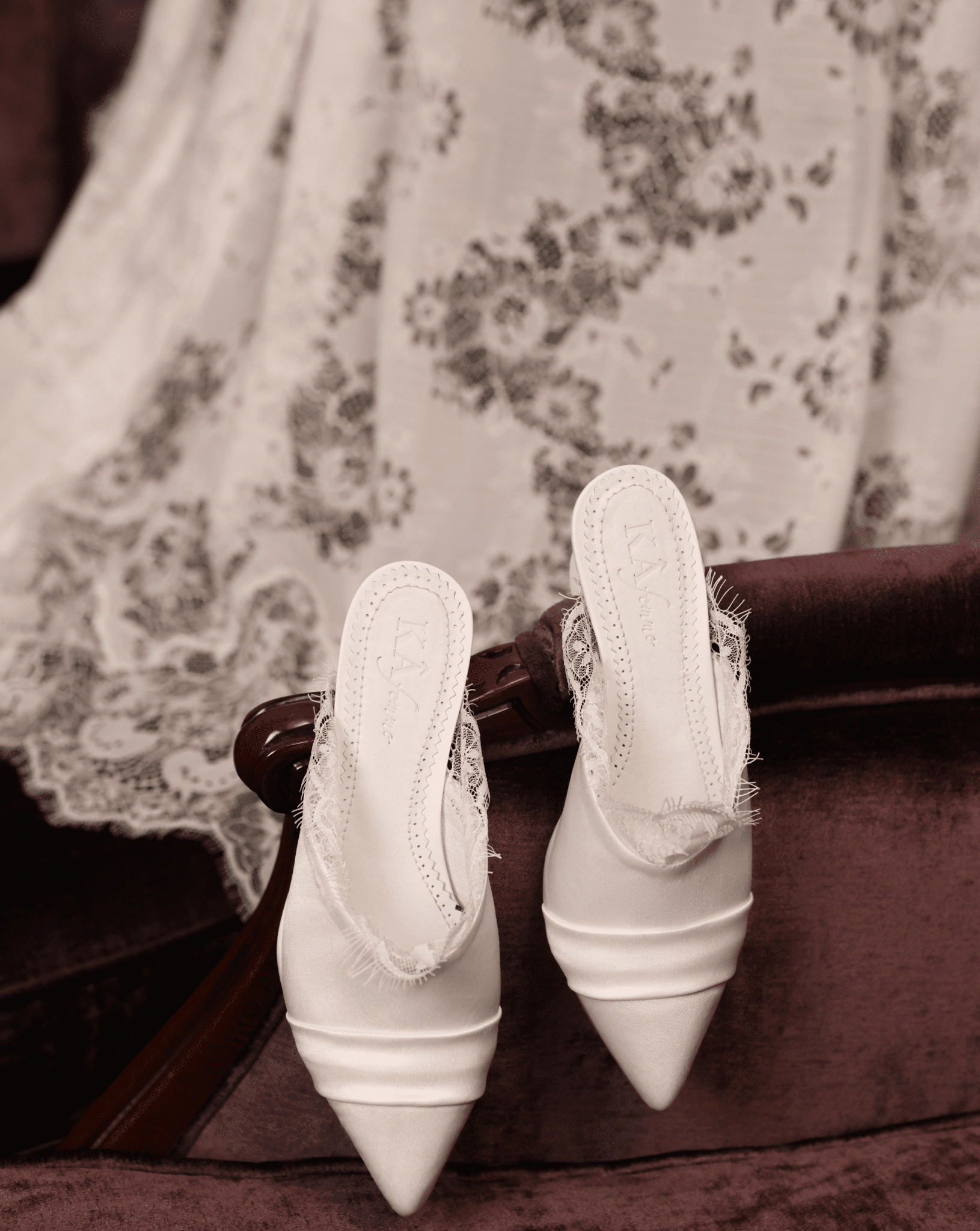 Creative shot of the Heeled Satin Slippers hanging on a chair, surrounded by delicate lace for a poetic home vibe.