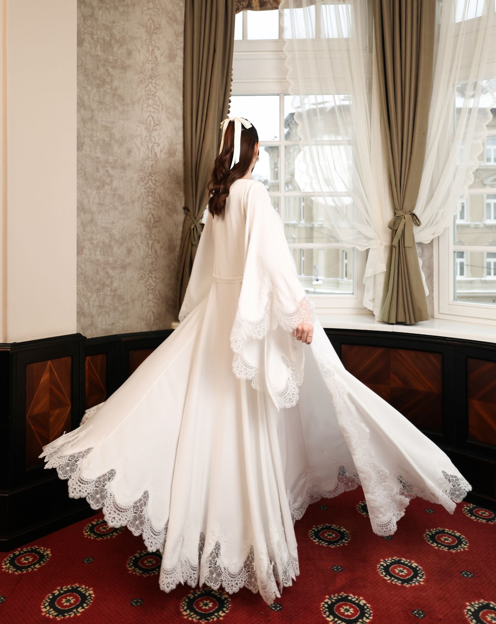 Dynamic rear view of the floor-length robe, highlighting the sweeping scalloped lace edges and soft cotton fabric.