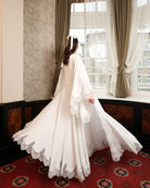 Dynamic rear view of the floor-length robe, highlighting the sweeping scalloped lace edges and soft cotton fabric.