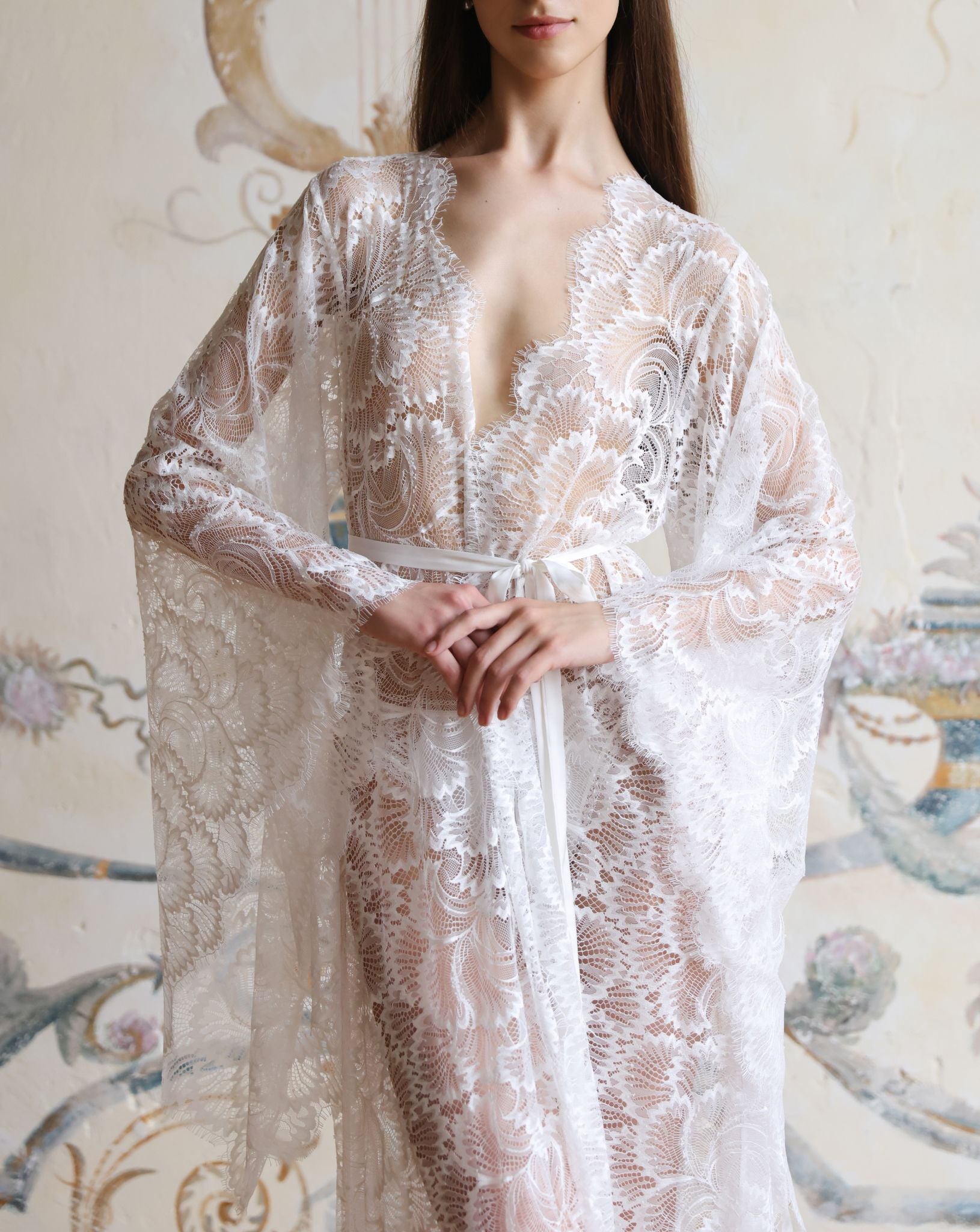 Detailed view from neck to knees of a bridal lace piece, focusing on the wrap-over style and delicate floral lace.