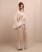 Side shot with a raised arm, showcasing the long sleeves with lace-embellished edges and refined finish.