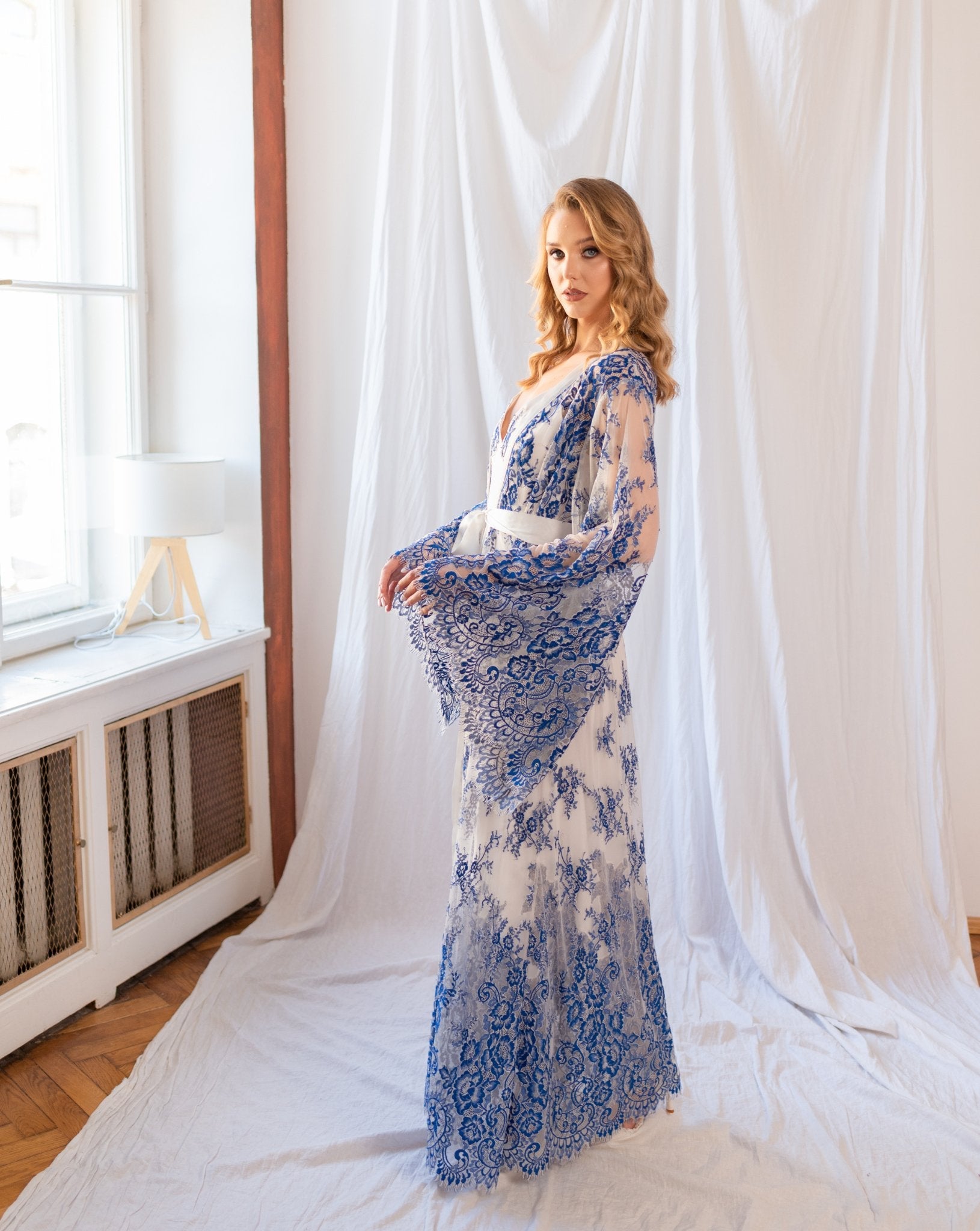 Model showing side of flowing blue and white lace robe