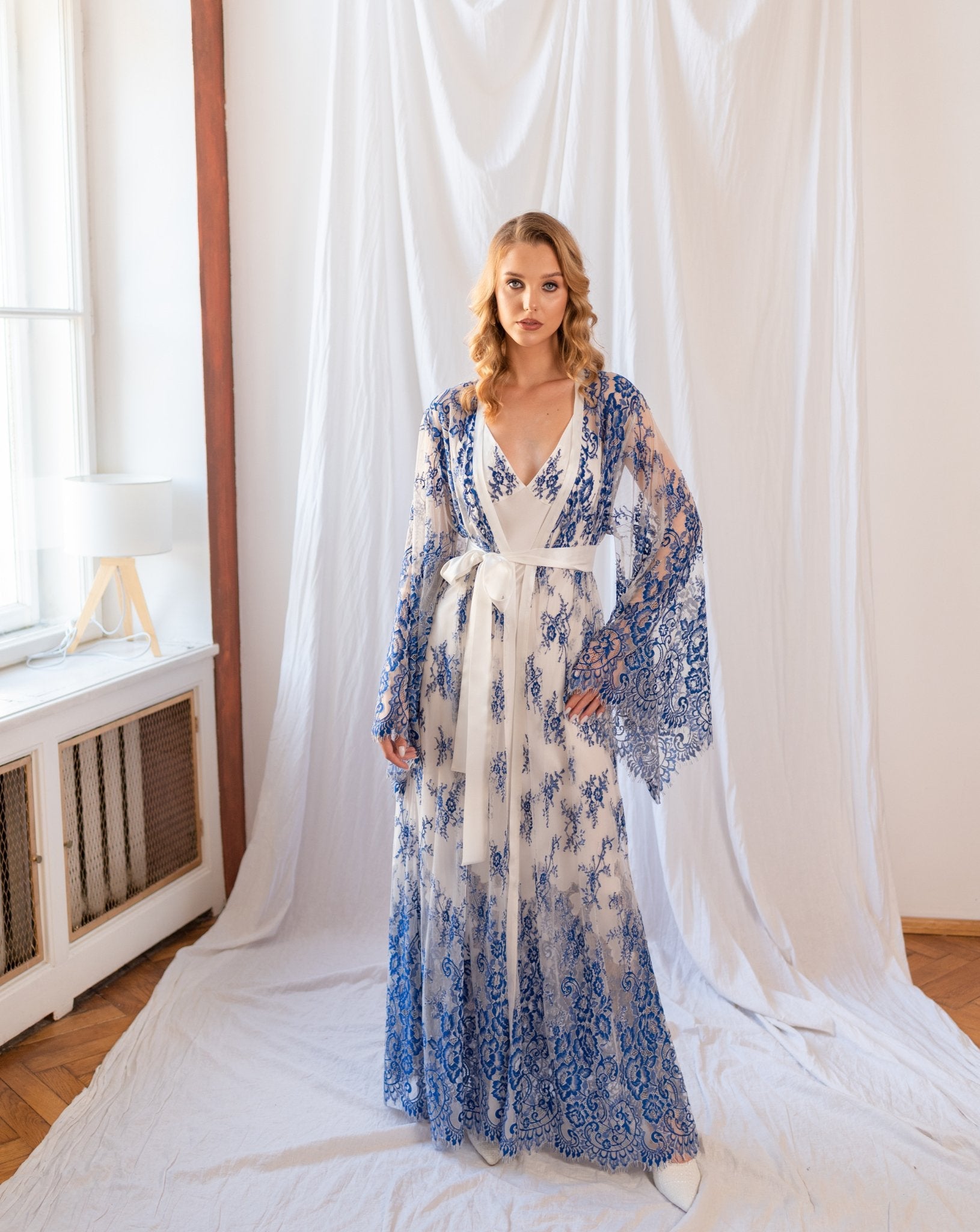 Model in long blue and white lace robe layered over silk nightgown