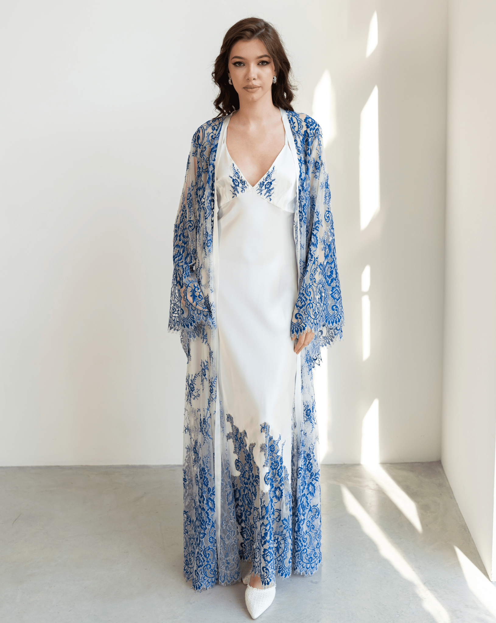 Model in long blue and white lace robe layered over silk nightgown