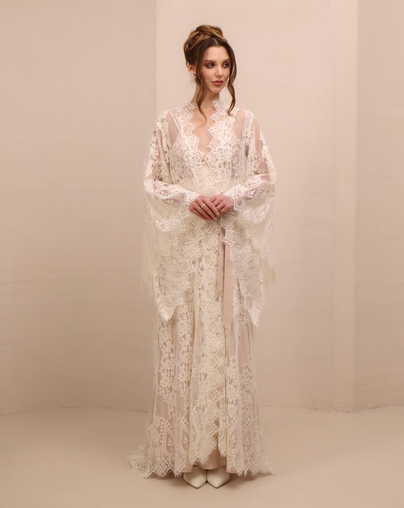 A poised frontal shot focusing on the wide sleeves of the lace robe, designed for elegance and presence.