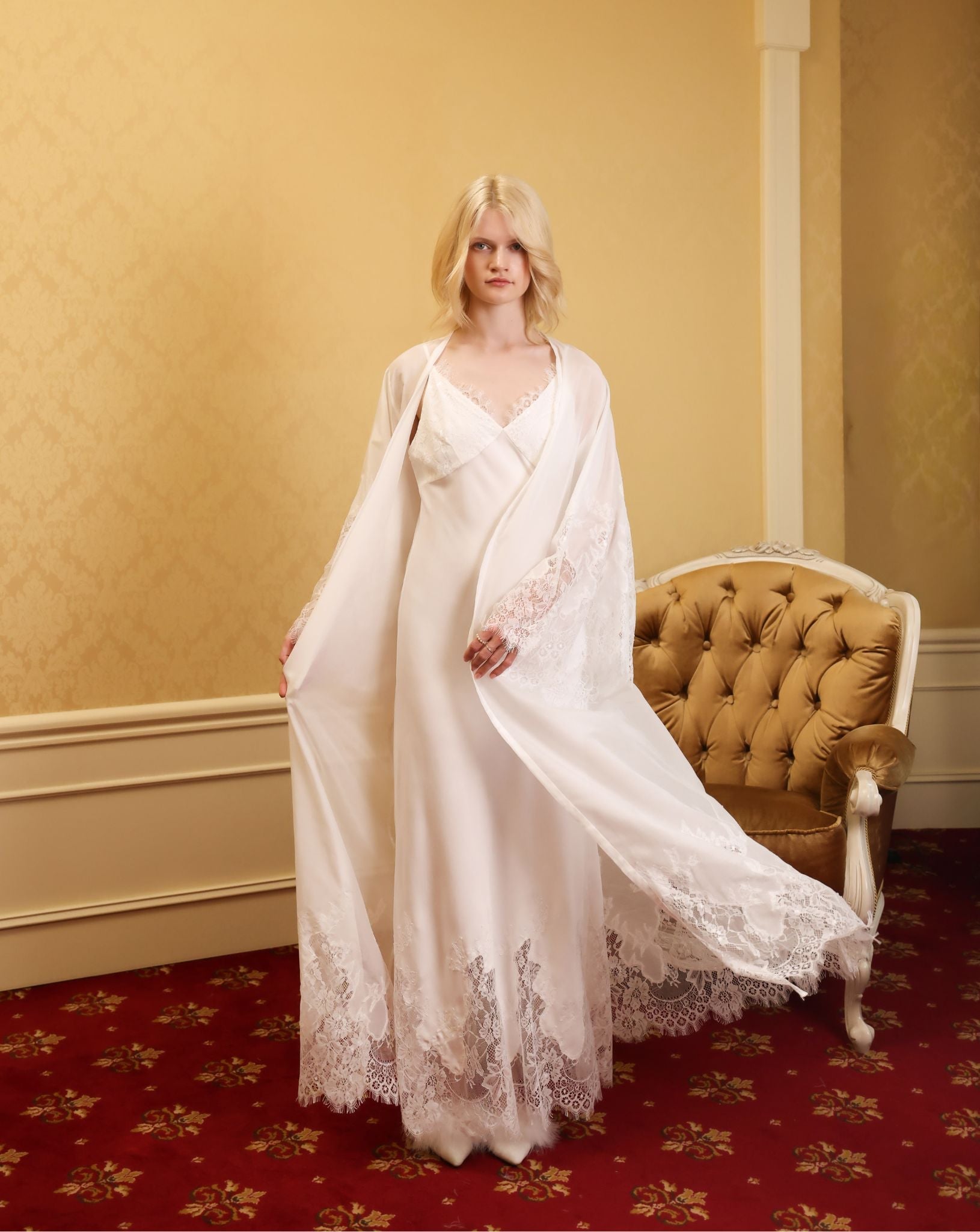 Full-length shot in a classic room, featuring the airy white robe with a flowing hem in a dynamic motion.