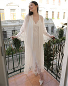 White Robe and Nightgown Set shown on a balcony, highlighting the sheer silk-cotton sleeves with fine lace edges.