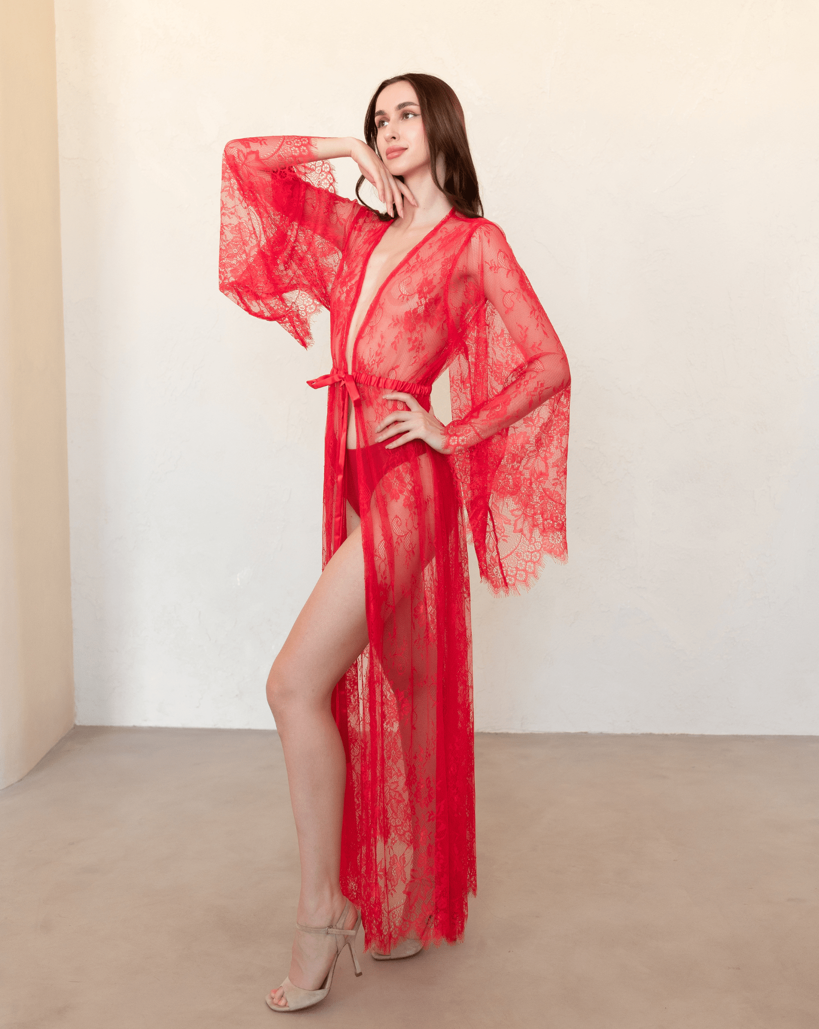 Red lace robe worn tied at the waist, showcasing the sheer texture and flowing sleeves.