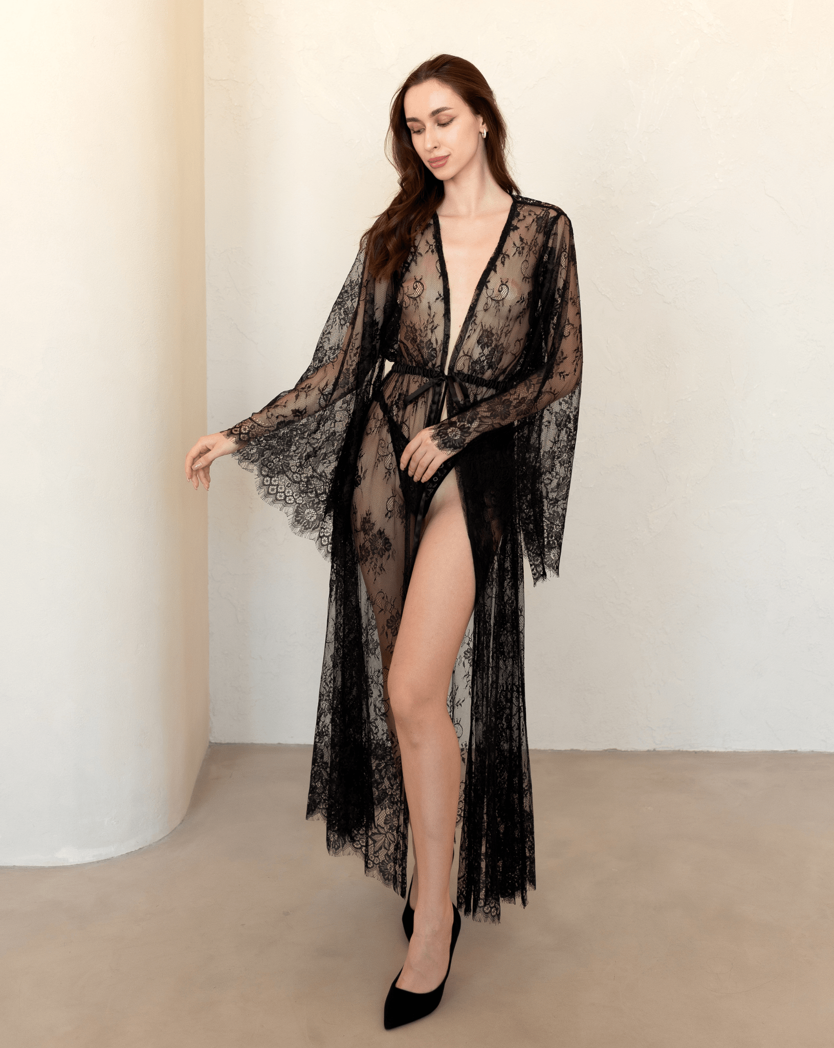 Elegant black lace robe worn loosely over lingerie, styled with heels and soft waves.