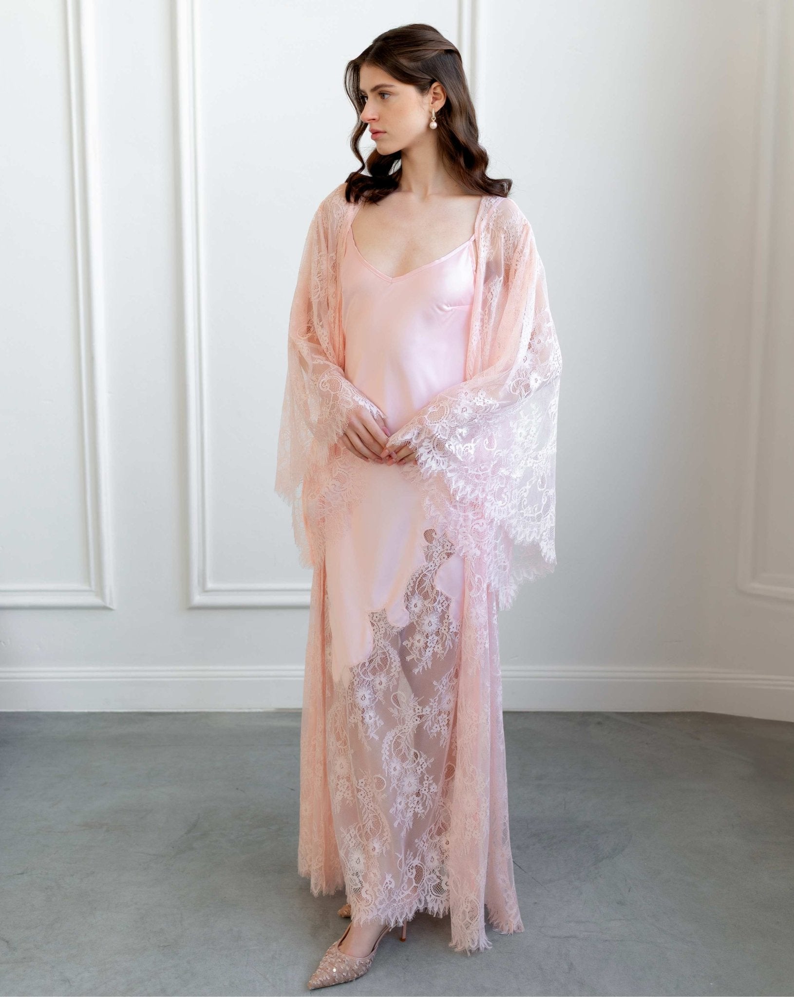 Bridal model in sheer pink lace set standing in minimalist white room