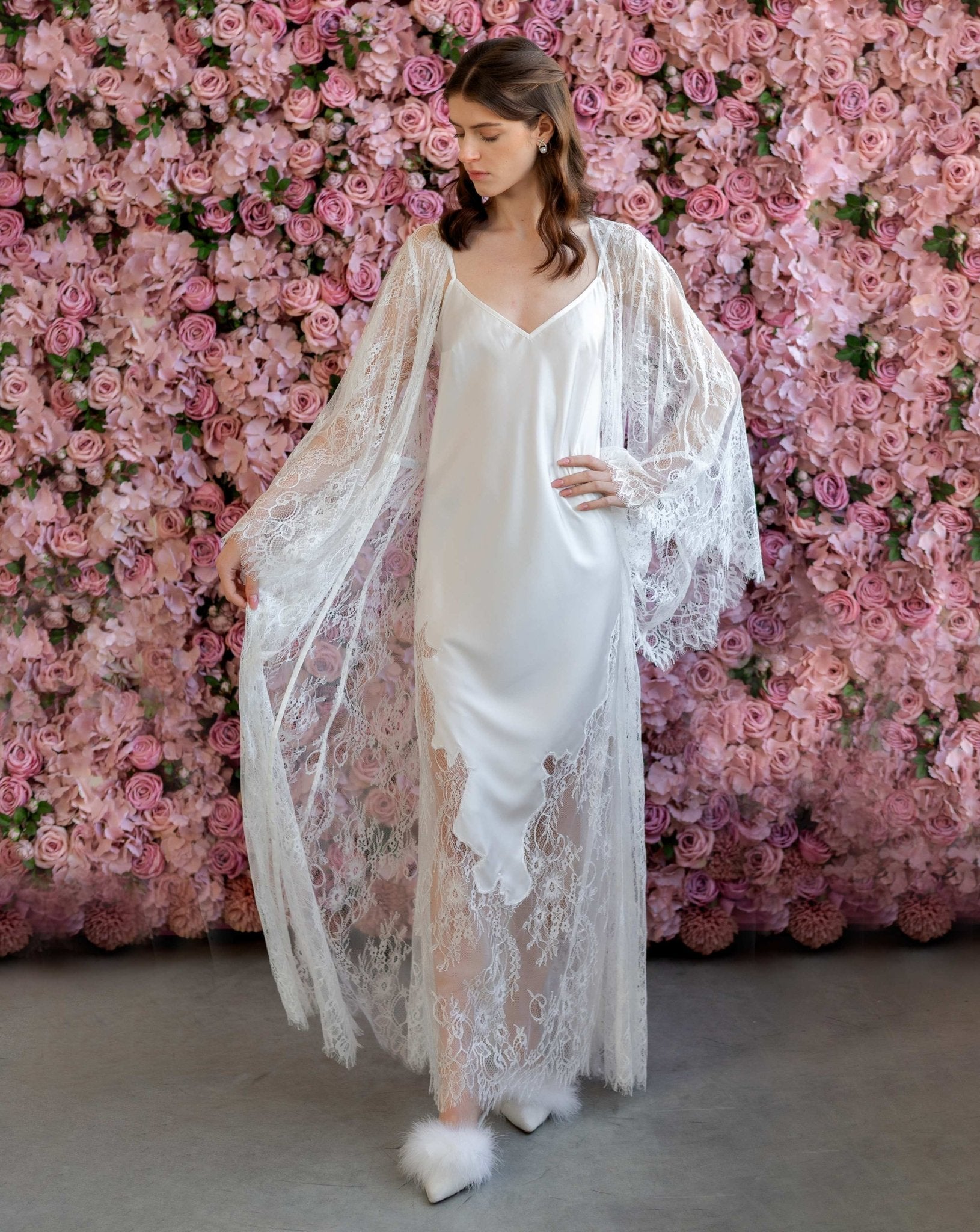 Woman in soft pink lace robe over white gown, standing in front of floral backdrop - Kafemme Loungewear