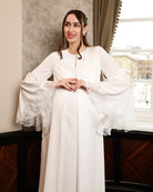 Mid-length shot of an expecting woman featuring wide sleeves with fine lace accents and a buttoned front.