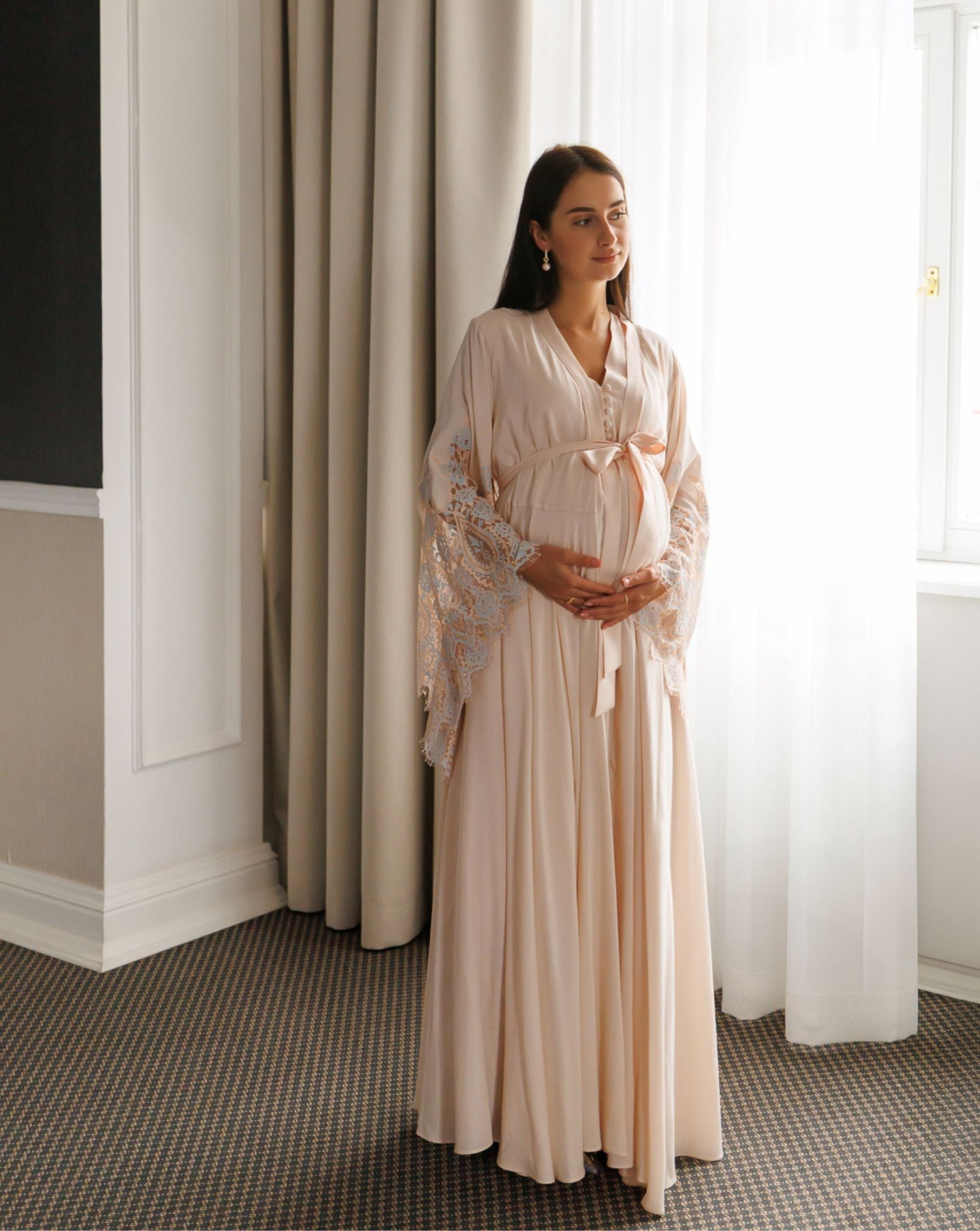 Pregnant woman in blush pink lace maternity robe and nightgown set by Kafemme