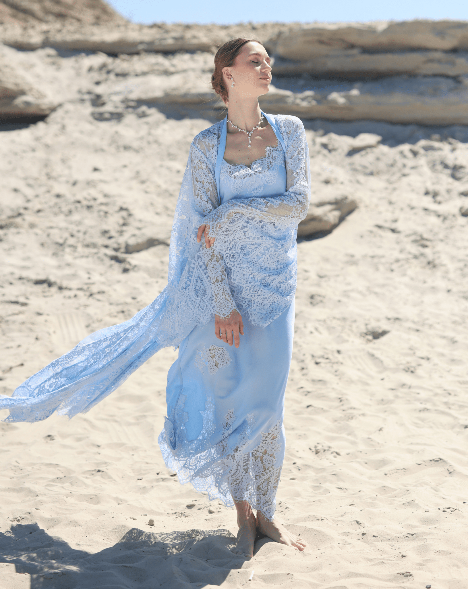 A dynamic shot of the Robe and Nightgown Set on the sand, capturing the artistic lace appliqués and flowing silhouette.