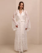 A frontal view with hands on hips, emphasizing the wide lace-finished sleeves and the defined waistline.