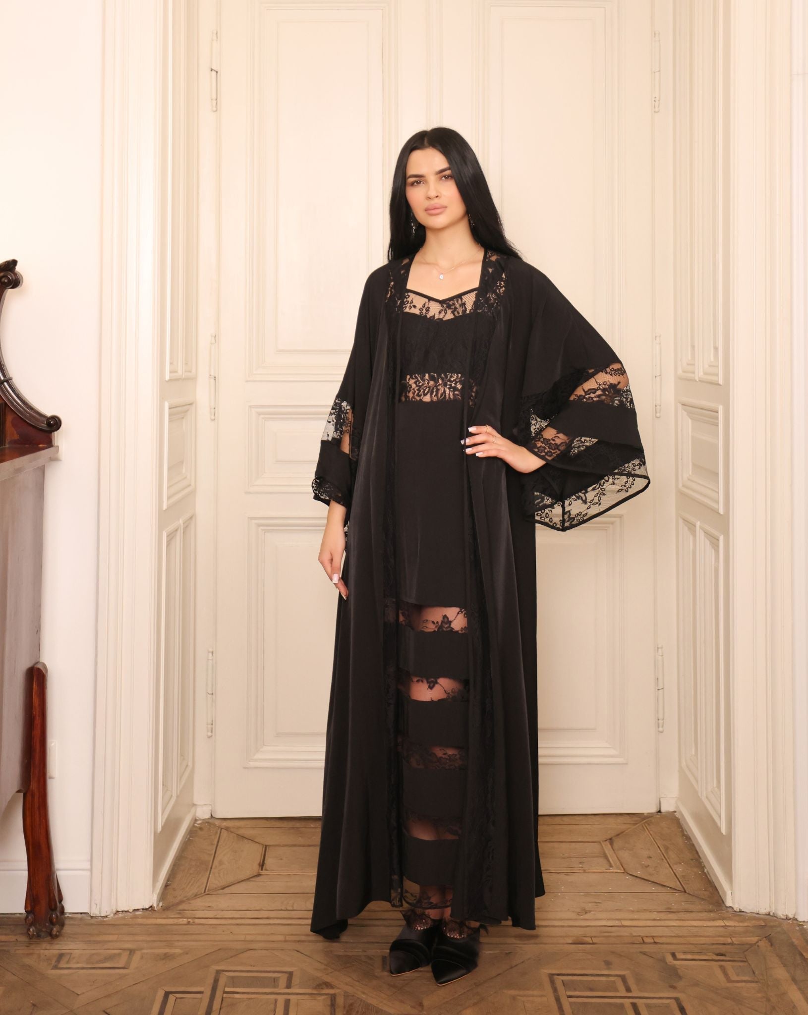 A sophisticated pose showcasing the delicate lace detailing at the sleeves and edges of the attire.