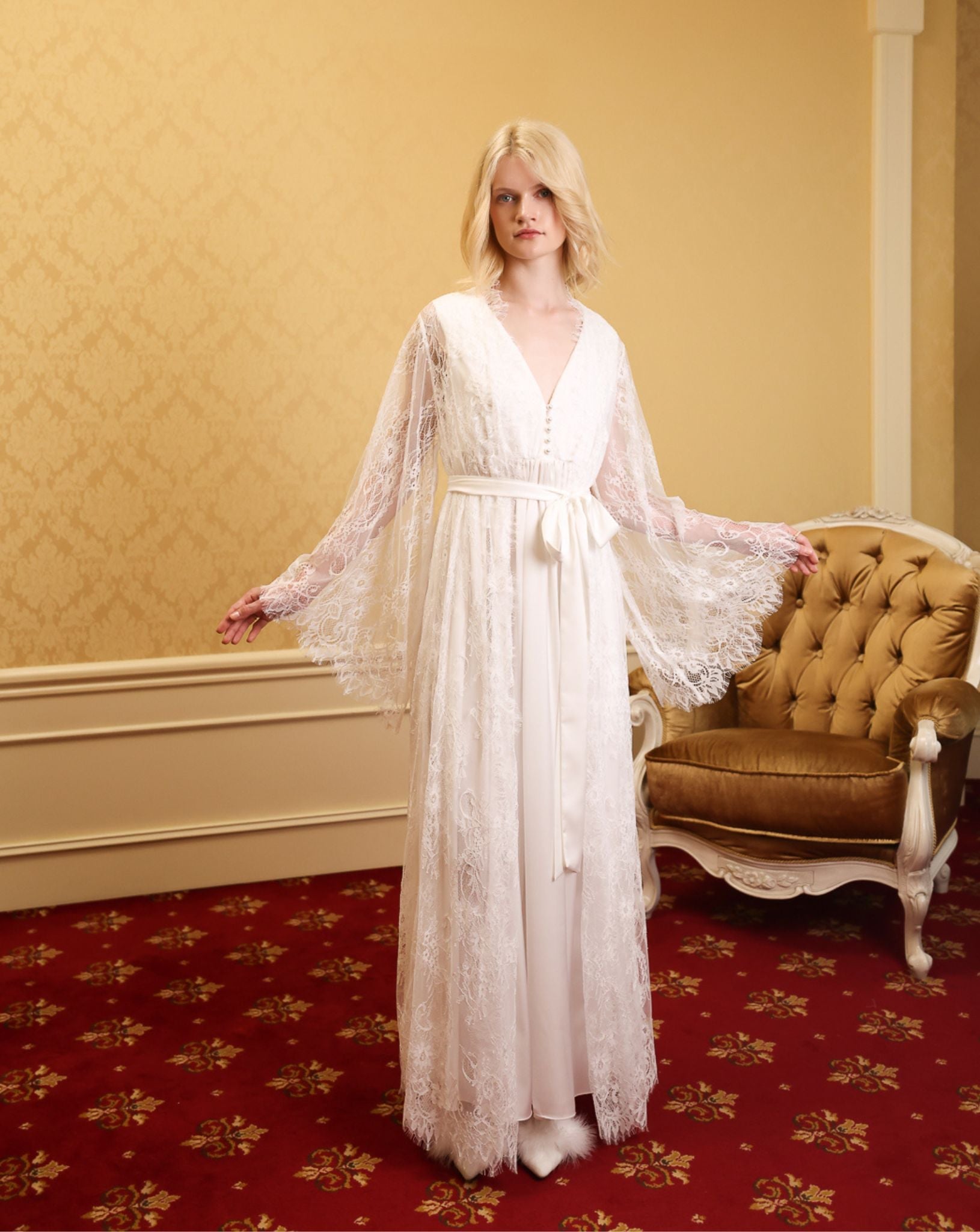 White Maternity Robe and Nightgown Set with both arms raised to show the long, airy lace butterfly sleeves.