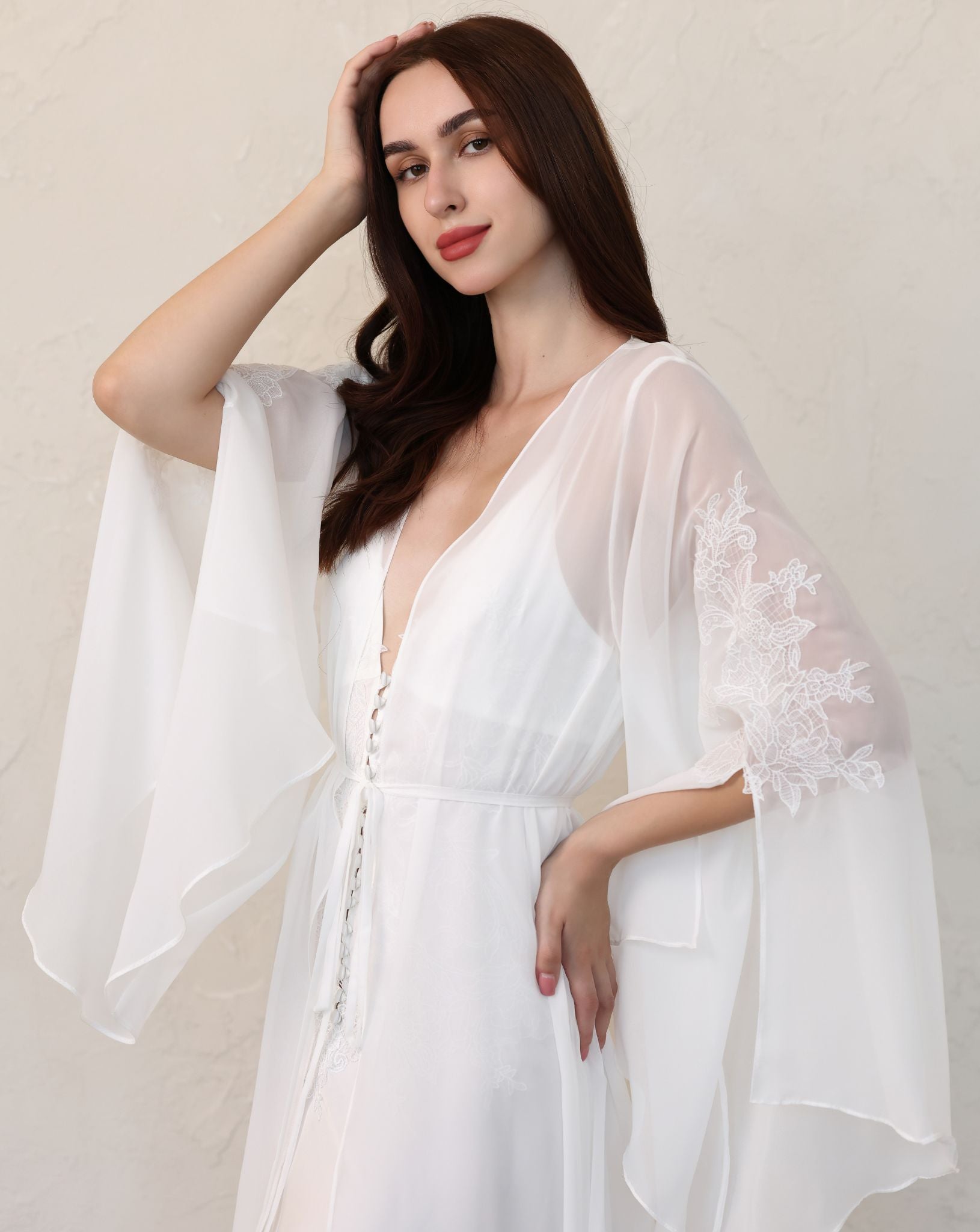 Waist-up shot in a sheer robe, showcasing wide sleeves with dramatic slits and delicate floral lace patterns.