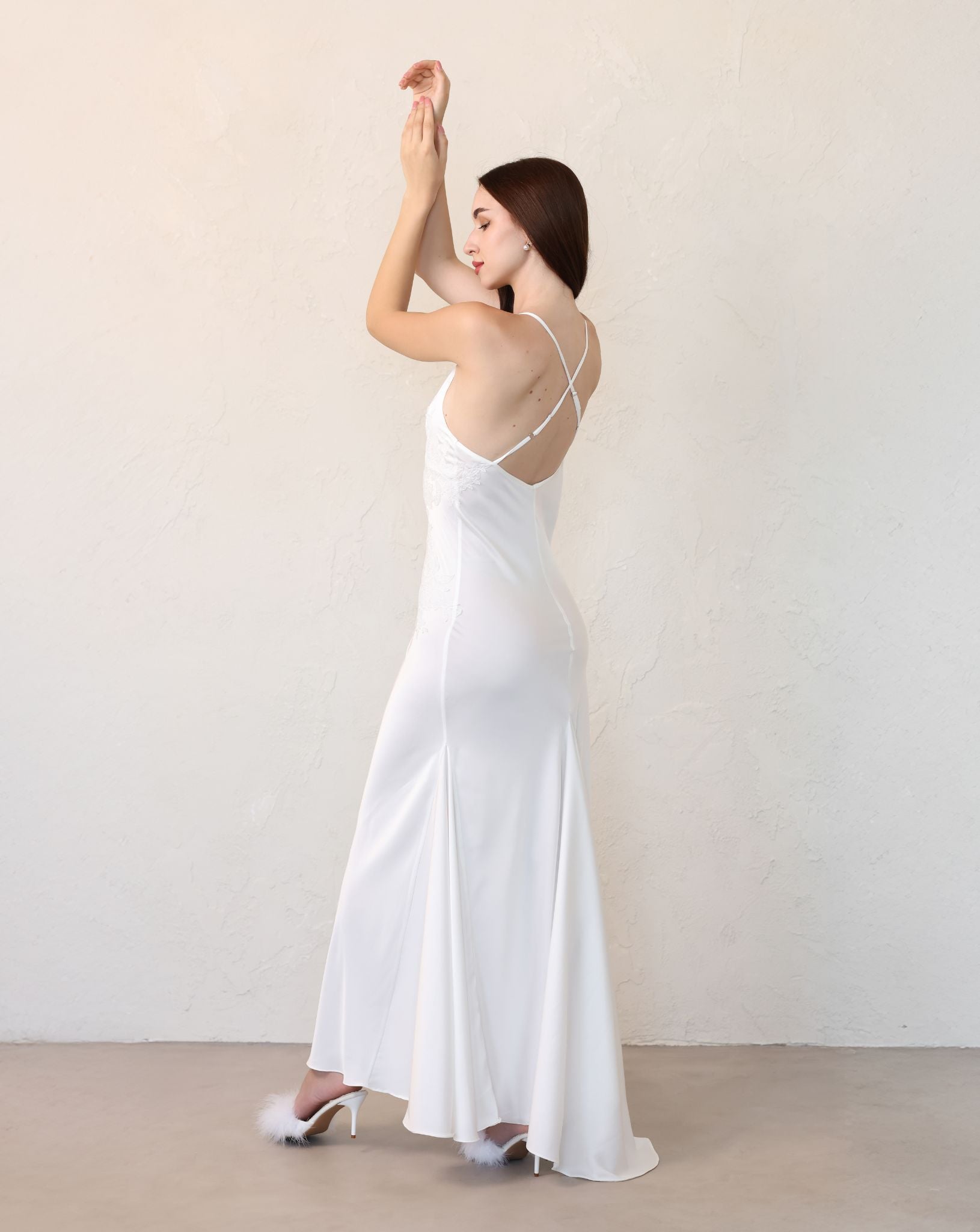 Rear view of a satin nightdress, highlighting the strappy back design and a graceful short train.