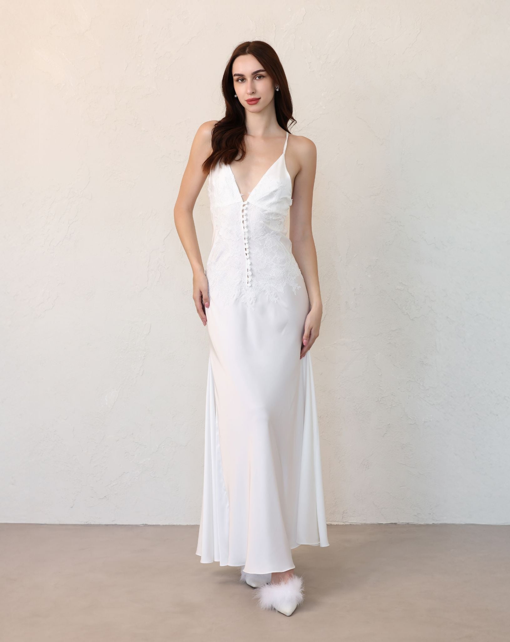 Front view of a white liquid satin nightgown with elegant lace embroidery and a row of decorative buttons.