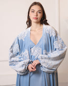 Shot from head to waist capturing the poetic movement of airy balloon sleeves with lace-trimmed wrists.