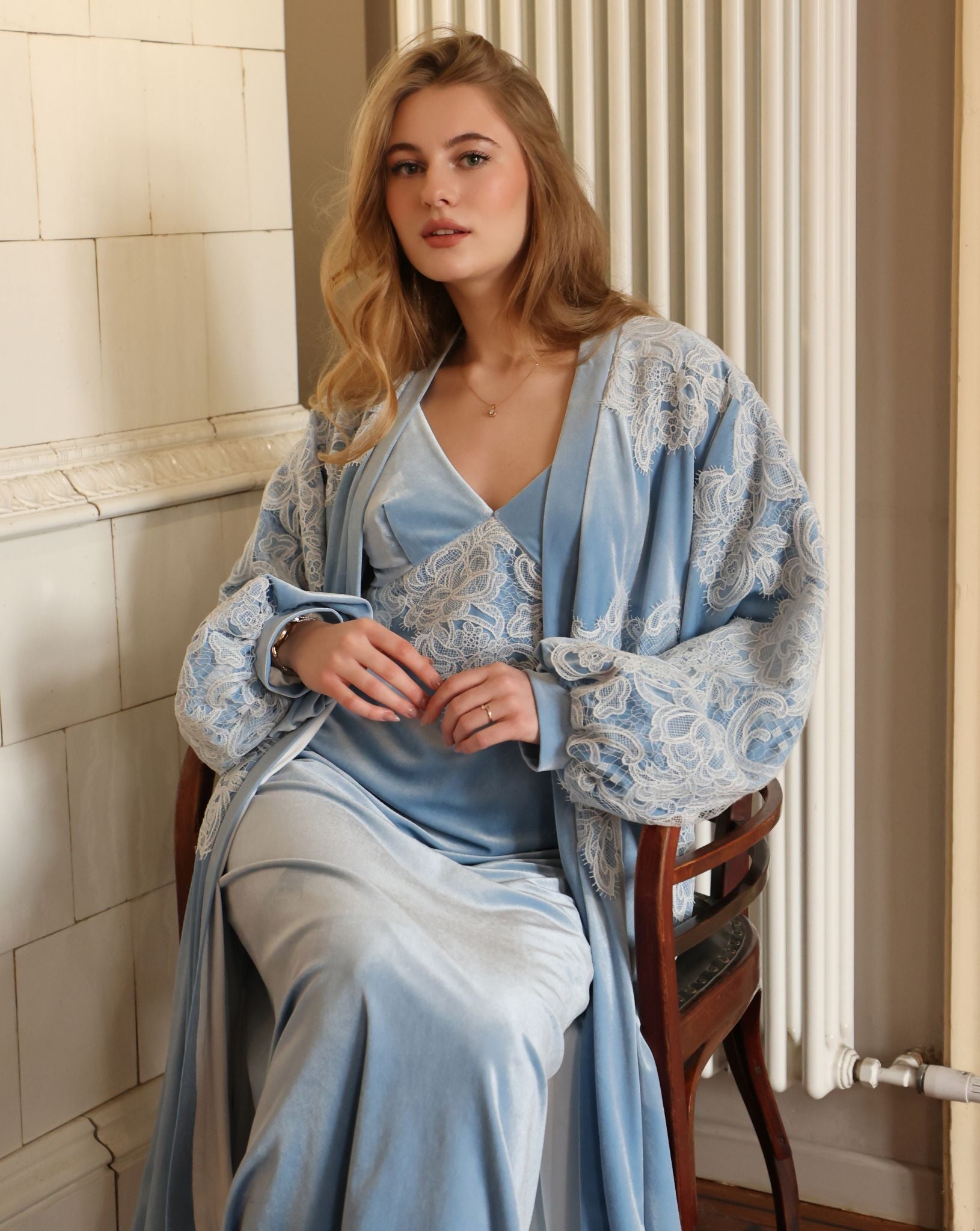 A seated shot of the velvet ensemble on a chair, showcasing the regal presence and plush texture of the voluminous robe.