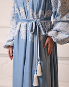 Close-up of a velvet tie at the waist, illustrating the elegant wrap-over style and rich texture of the garment.