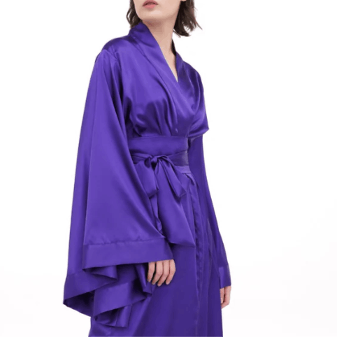 Close-up of a purple satin garment from neck to knees, highlighting the wide obi-style belt and structural sleeve lines.