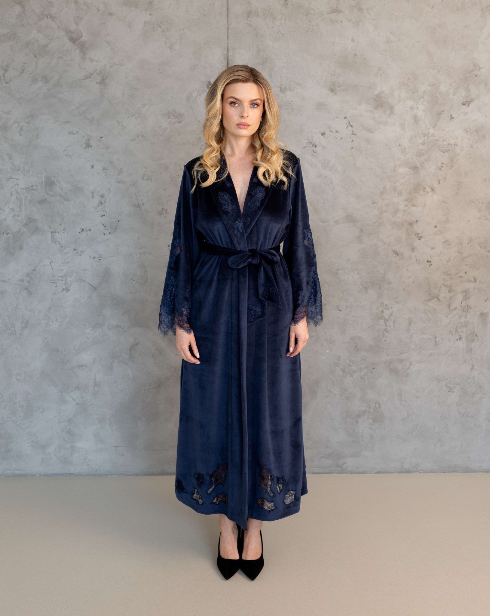 Front view of the long blue velvet kimono with intricate lace detailing on the sleeves and collar, standing straight.