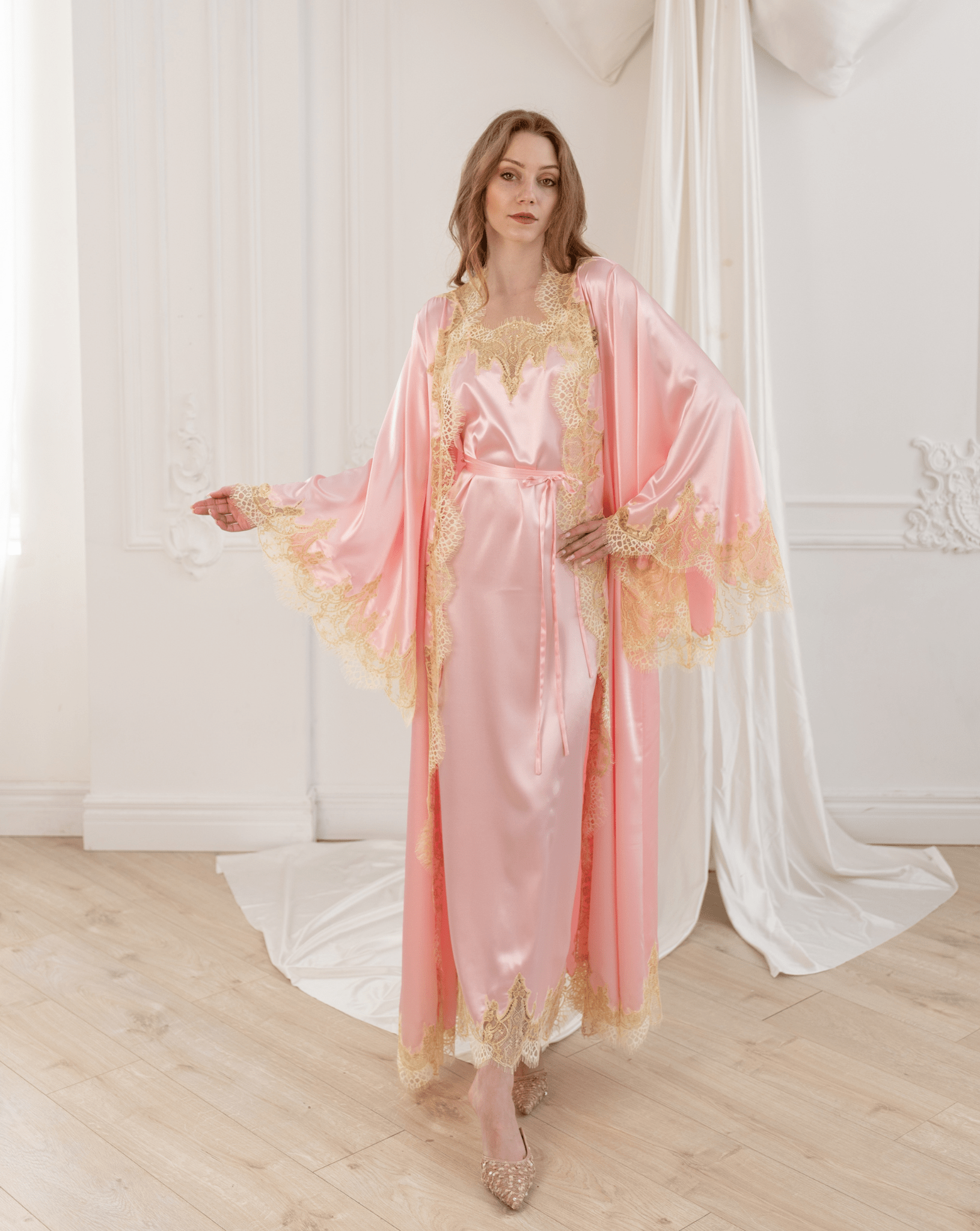 Standing in a graceful pose with one hand on the waist, highlighting the refined silhouette and floor-length drape.