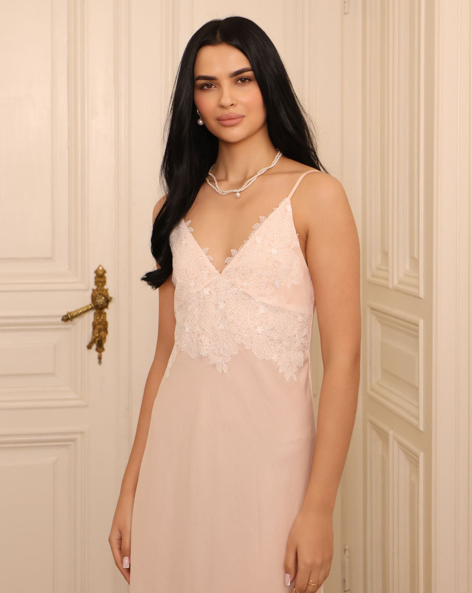 Mid-length shot focusing on the intricate lace at the neckline, illustrating the romantic restraint of the design.