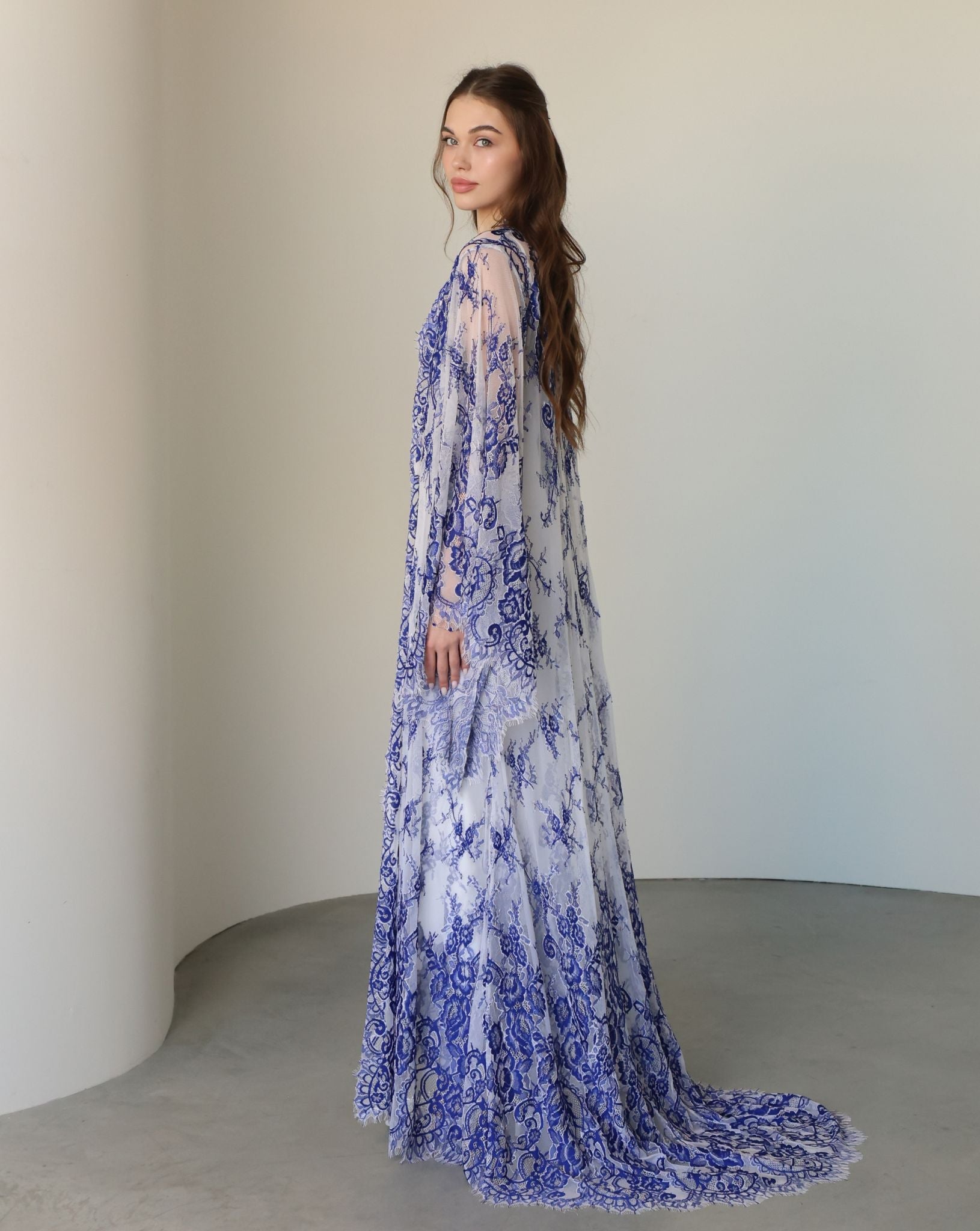 Side perspective of the attire, highlighting the graceful flow of the long lace train and the soft fabric.