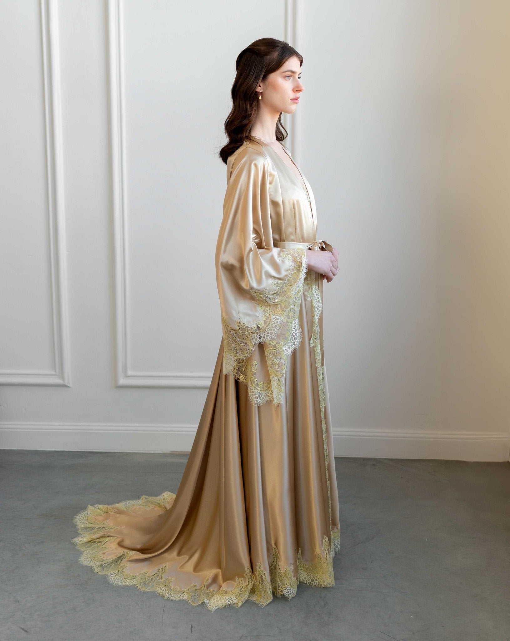 Side profile of the satin robe, highlighting the dramatic flowing train and wide lace-trimmed sleeves.