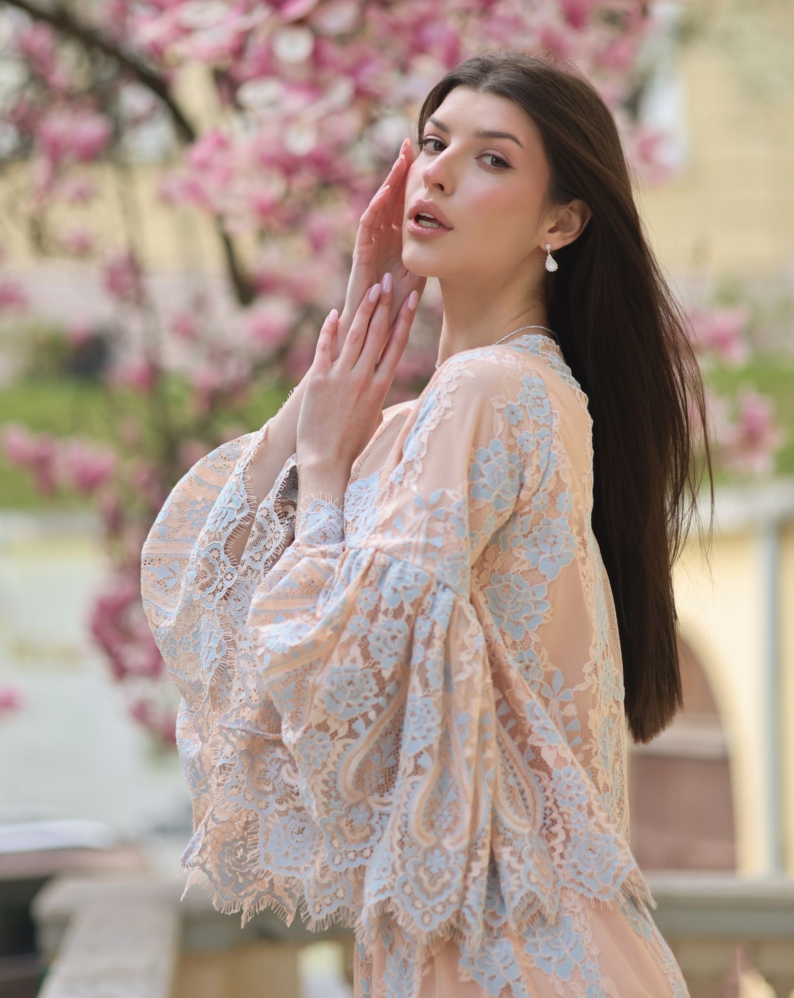 An artistic shot of a woman in a pajama set against a blooming magnolia, blending natural beauty with refined home wear.