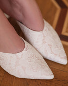 Close-up of the slippers on feet, focusing on the delicate French lace adornment and high-quality satin texture.