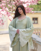 A mid-length shot of the full Pyjamas set with hands on the waist to highlight the wide, lace-embellished sleeves.