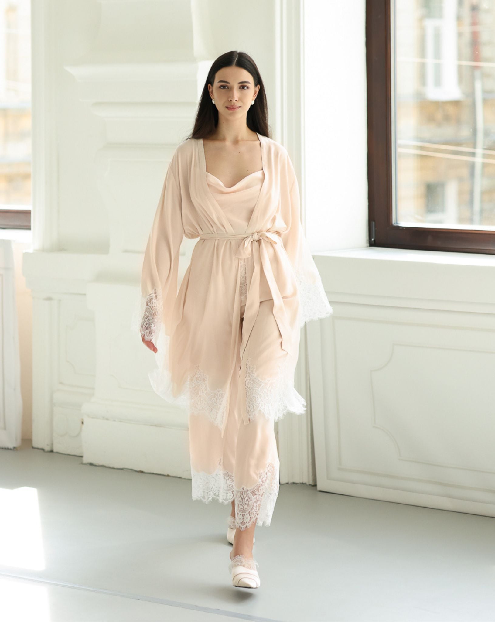 Full-length view of a woman walking in a belted cotton-viscose robe, showcasing an elegant and fluid home look.
